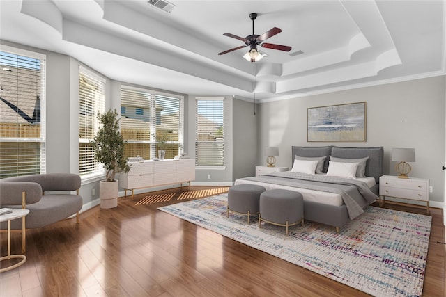 bedroom with visible vents, multiple windows, a raised ceiling, and wood finished floors