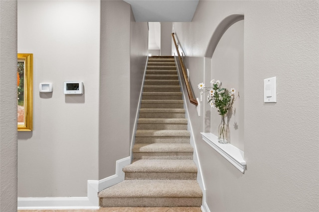 stairway with arched walkways and baseboards