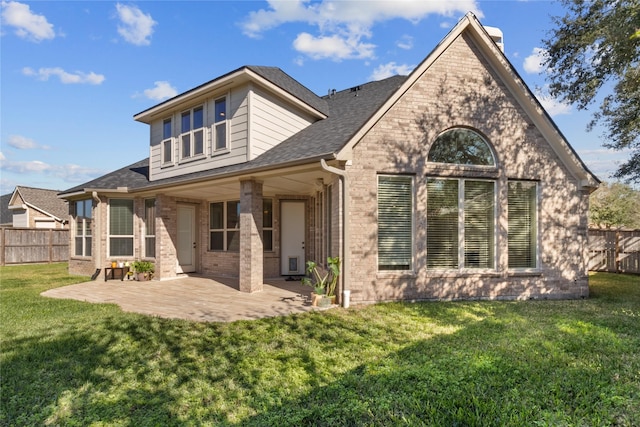 back of property with a patio, fence, brick siding, and a lawn