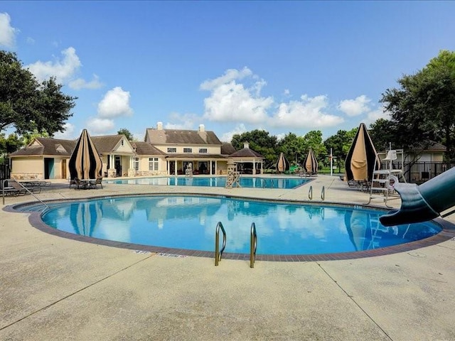 pool with a patio area and a water slide