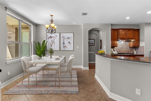 dining area featuring visible vents, a notable chandelier, arched walkways, light tile patterned floors, and baseboards