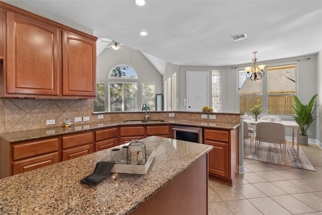 kitchen with tasteful backsplash, visible vents, a peninsula, light tile patterned flooring, and a sink