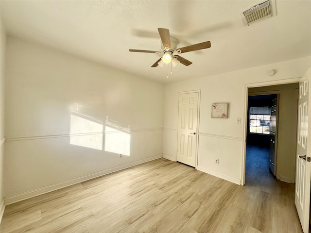 unfurnished bedroom with a ceiling fan, light wood-style floors, visible vents, and baseboards