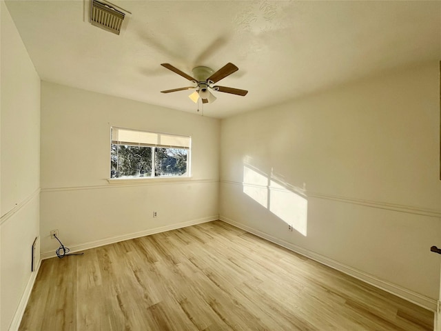 empty room with light wood-style flooring, a ceiling fan, visible vents, and baseboards