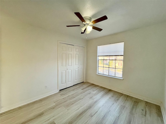 unfurnished bedroom featuring a ceiling fan, baseboards, a closet, and light wood finished floors