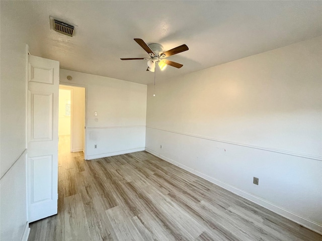 empty room featuring baseboards, light wood-style floors, visible vents, and ceiling fan