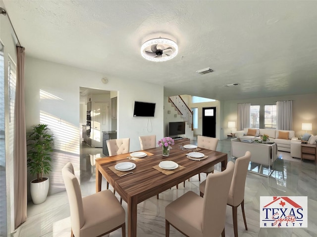 dining area with visible vents, a textured ceiling, ceiling fan, and stairway