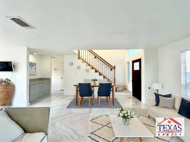 living area featuring stairs, baseboards, visible vents, and marble finish floor