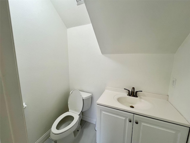 bathroom featuring toilet, vanity, baseboards, and vaulted ceiling