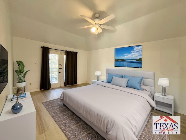 bedroom featuring baseboards, light wood-style floors, and vaulted ceiling