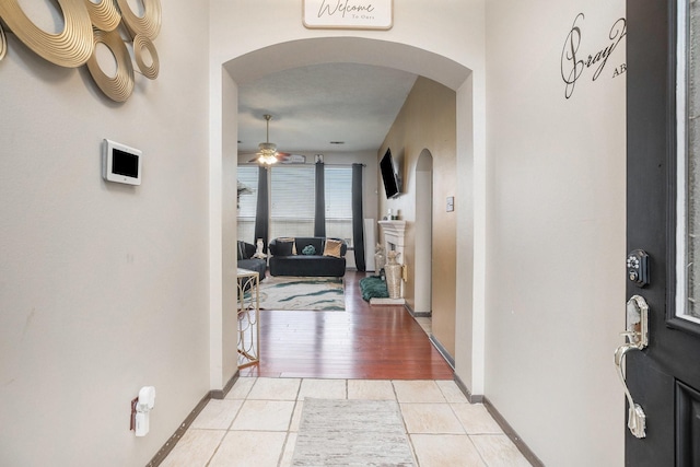 hallway with baseboards, arched walkways, and light tile patterned flooring