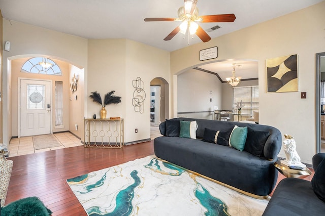 living area featuring wood finished floors, ceiling fan with notable chandelier, arched walkways, and a healthy amount of sunlight