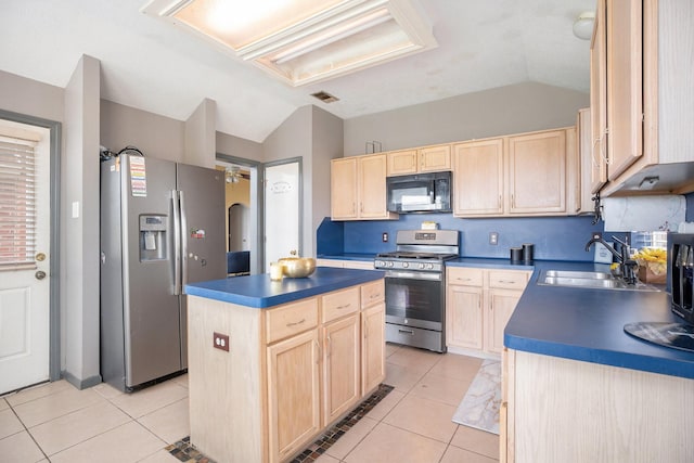 kitchen with dark countertops, light brown cabinetry, lofted ceiling, appliances with stainless steel finishes, and a sink