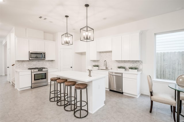 kitchen with visible vents, a center island, appliances with stainless steel finishes, a notable chandelier, and a sink