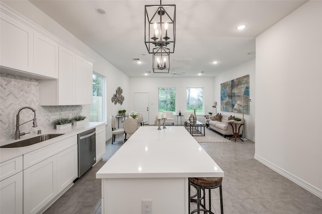 kitchen with a sink, backsplash, stainless steel dishwasher, a center island, and a chandelier