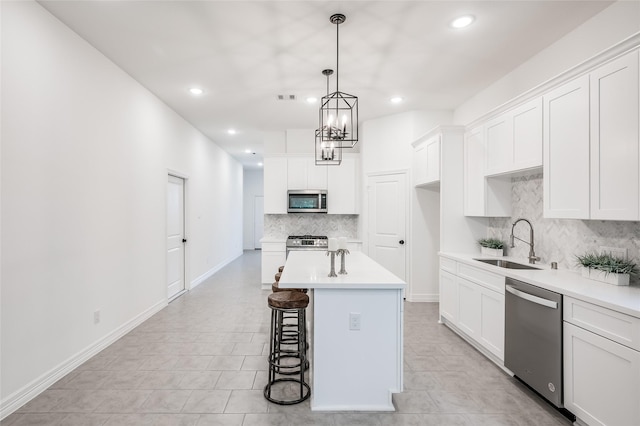 kitchen with a kitchen bar, white cabinets, appliances with stainless steel finishes, and a sink