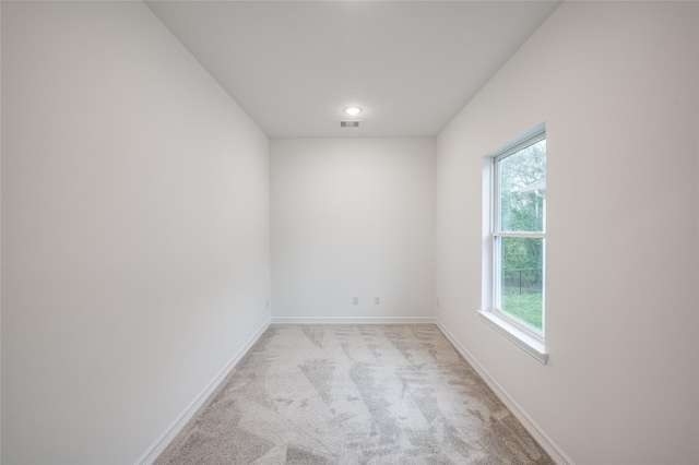 unfurnished room featuring visible vents, baseboards, and light colored carpet