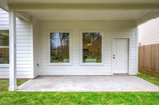 view of exterior entry featuring a patio and fence