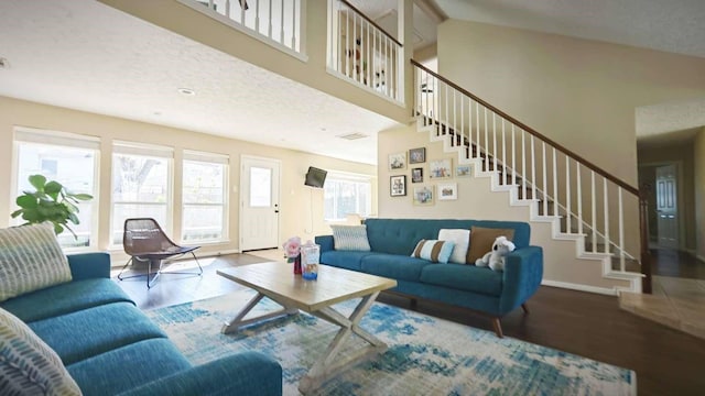 living room featuring stairway, baseboards, a high ceiling, and wood finished floors