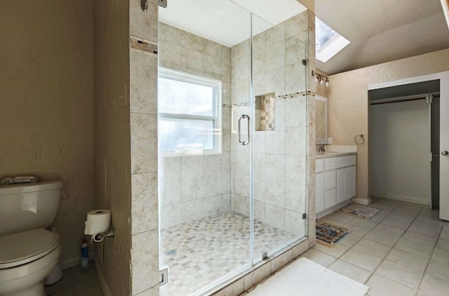 bathroom featuring vanity, a skylight, a stall shower, tile patterned floors, and toilet