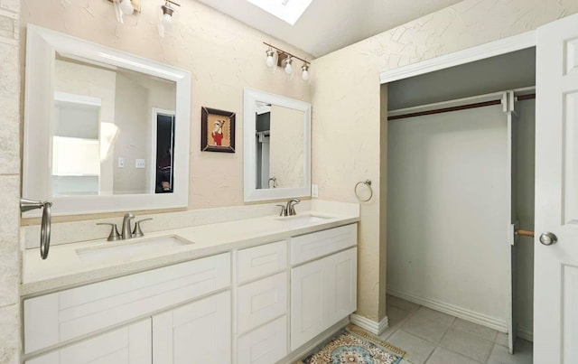 bathroom featuring double vanity, a skylight, tile patterned floors, and a sink