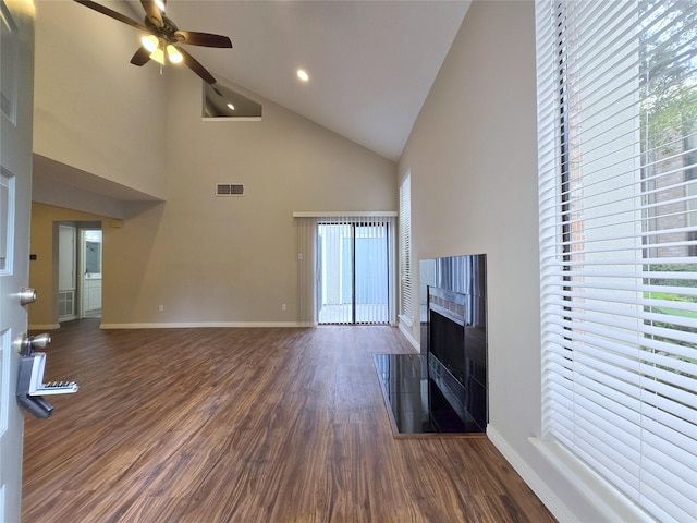 unfurnished living room featuring visible vents, dark wood-type flooring, a fireplace with raised hearth, baseboards, and ceiling fan