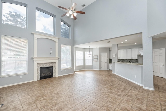 unfurnished living room with visible vents, a fireplace, baseboards, and ceiling fan