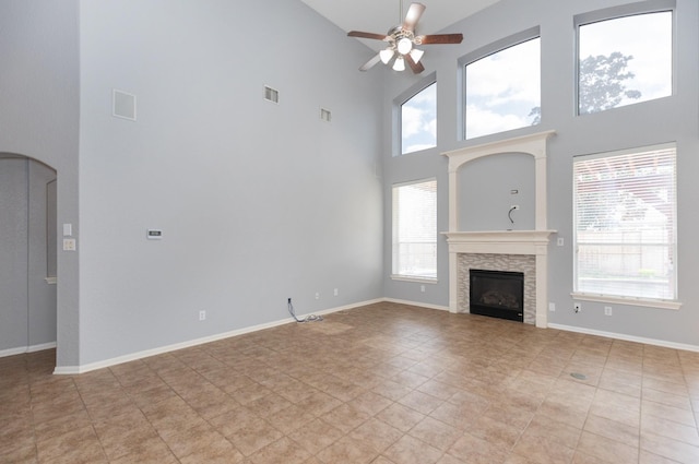 unfurnished living room with a stone fireplace, a ceiling fan, visible vents, and baseboards