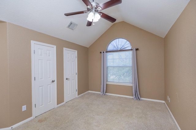 unfurnished bedroom featuring visible vents, a ceiling fan, baseboards, carpet flooring, and lofted ceiling