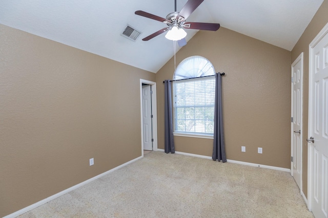 carpeted empty room with visible vents, lofted ceiling, baseboards, and a ceiling fan