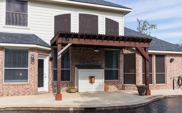view of front facade featuring a patio, brick siding, roof with shingles, and a pergola
