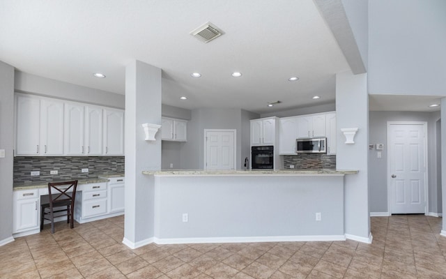 kitchen with visible vents, stainless steel microwave, black oven, white cabinetry, and baseboards