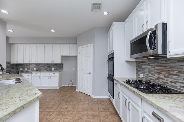 kitchen with a sink, visible vents, black appliances, and white cabinetry