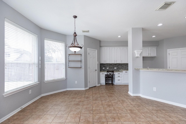 kitchen with white cabinetry, baseboards, visible vents, and backsplash