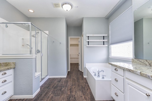 bathroom with vanity, wood finished floors, a shower stall, a walk in closet, and a bath