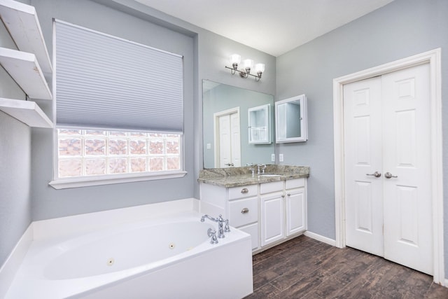 full bathroom featuring a jetted tub, vanity, baseboards, and wood finished floors