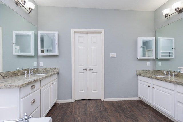 bathroom with a sink, baseboards, two vanities, and wood finished floors