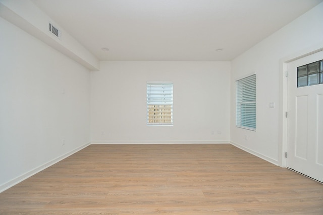 empty room with baseboards, visible vents, and light wood finished floors