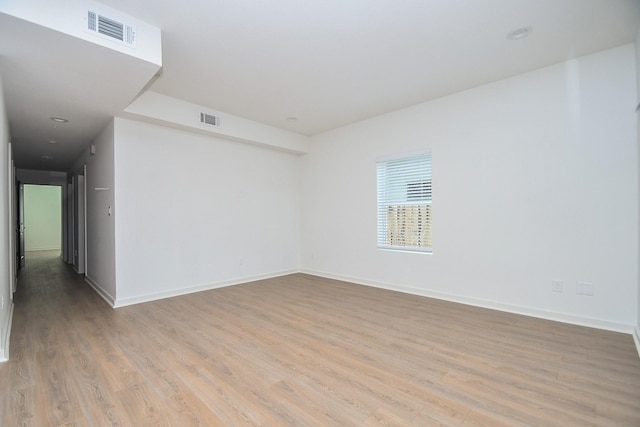 empty room with light wood-style flooring, baseboards, and visible vents