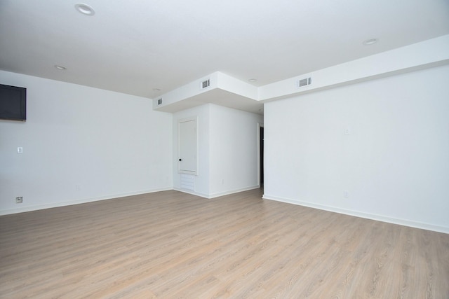 empty room featuring visible vents, baseboards, and light wood finished floors