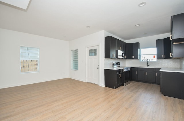 kitchen featuring dark cabinetry, tasteful backsplash, appliances with stainless steel finishes, and a sink