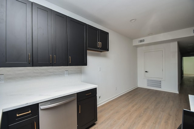 kitchen featuring stainless steel dishwasher, dark cabinetry, light wood-style floors, and backsplash