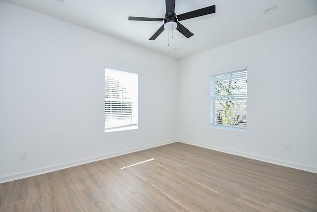 spare room featuring baseboards, light wood finished floors, and ceiling fan