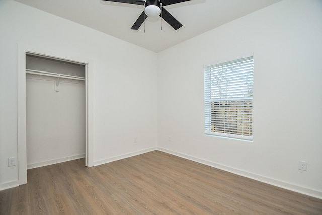 unfurnished bedroom with a closet, a ceiling fan, baseboards, and wood finished floors