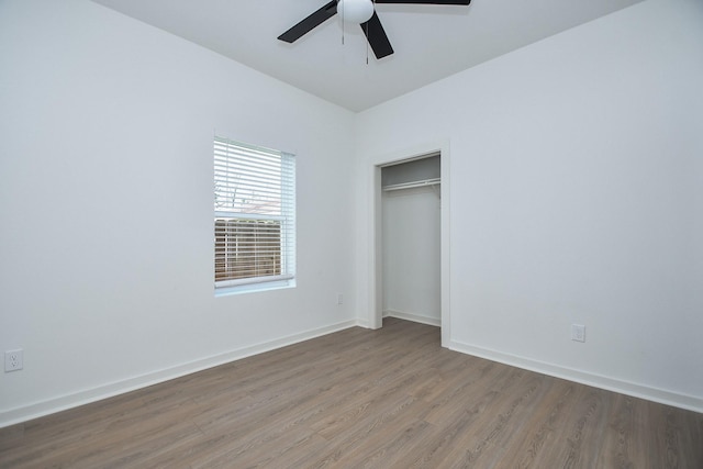 unfurnished bedroom featuring a closet, a ceiling fan, baseboards, and wood finished floors