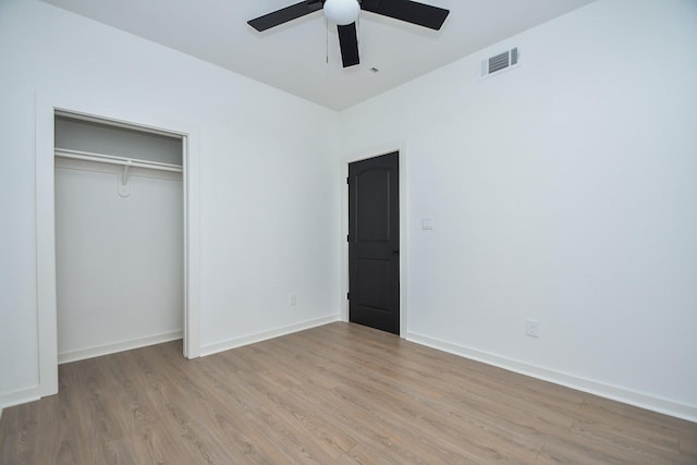 unfurnished bedroom featuring a ceiling fan, wood finished floors, visible vents, baseboards, and a closet