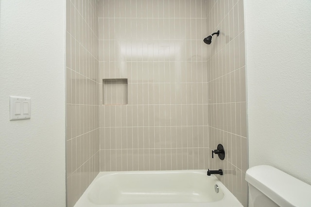 bathroom with a textured wall, toilet, and shower / tub combination