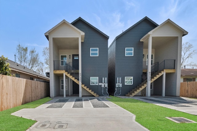 modern home featuring stairs, a front lawn, and fence