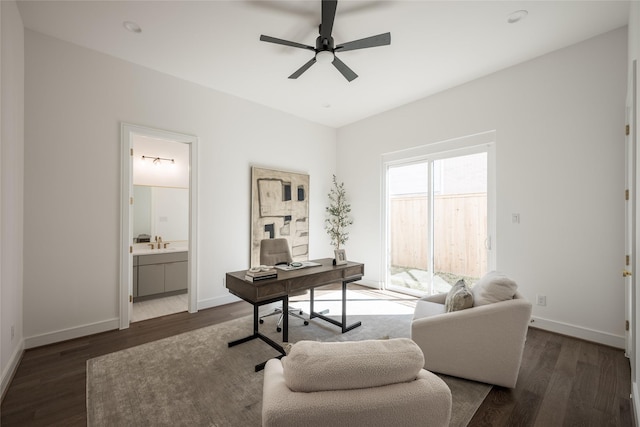 home office featuring a sink, baseboards, wood finished floors, and ceiling fan