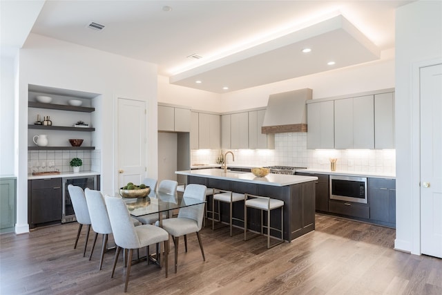 kitchen with visible vents, premium range hood, wine cooler, appliances with stainless steel finishes, and a kitchen breakfast bar